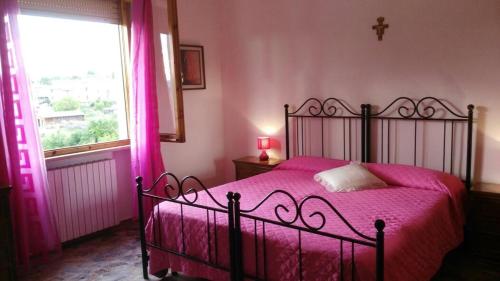 a bedroom with a bed with pink sheets and a window at Il Giardino del Gallo in Foligno