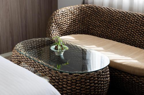 a rattan chair with a glass table with a plant at パプリカホテルです in Kisarazu