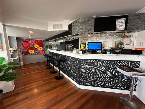 a bar with a black and white counter and chairs at Highpoint International Hotel in Gladstone