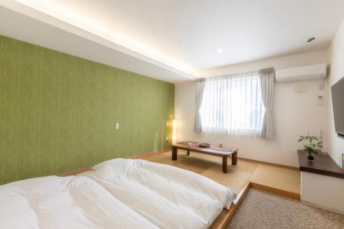 a bedroom with a white bed and a green wall at パプリカホテルです in Kisarazu
