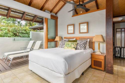 um quarto com uma cama e uma varanda com cadeiras em Far Pavilion A - Stylish Villa with Tropical Views em Port Douglas