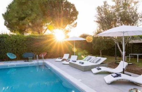 a swimming pool with chairs and umbrellas next to a pool at Bombana Beach Apartments in Fontane Bianche