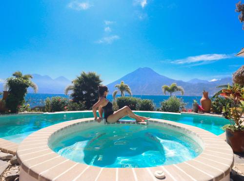 a woman is sitting in a swimming pool at Kula Maya Boutique Hotel and Spa in San Marcos La Laguna