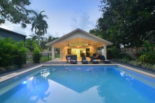 a swimming pool with chairs and a house at The Red Anchor in Port Douglas