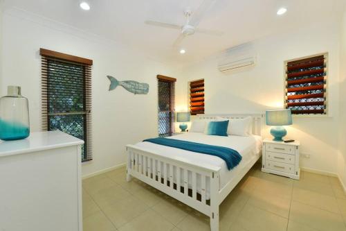 a white bedroom with a bed and a window at The Red Anchor in Port Douglas