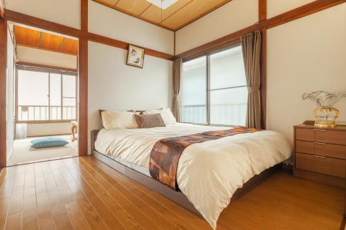 a bedroom with a large bed with windows at KiraKira House Elegant 3BR on Yamanote Line in Tokyo