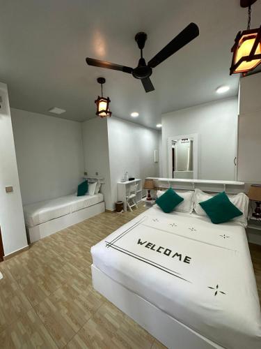 a bedroom with a large white bed with green pillows at Island Luxury Dive Hotel - Fulhadhoo in Fulhadhoo