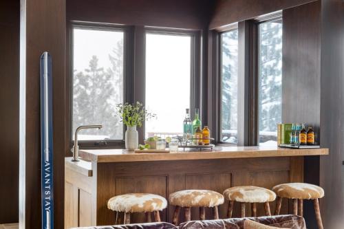 a kitchen with a counter with stools and windows at Bronson by AvantStay Luxurious Home On The Slopes in Olympic Valley