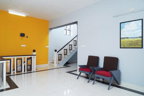 a hallway with two chairs and a staircase at ORANGE VALLEY TOWN RESIDENCY in Trivandrum