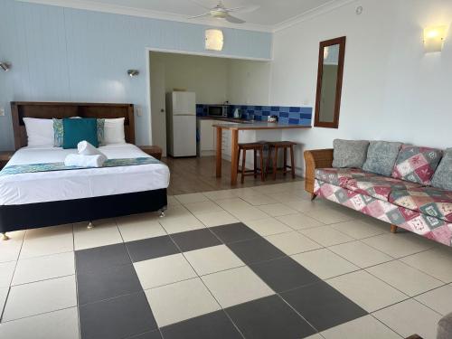 a bedroom with a bed and a couch at Cardwell Beachfront Motel in Cardwell
