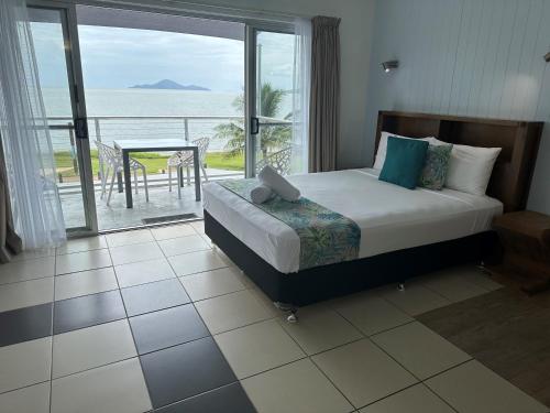 1 dormitorio con cama y vistas al océano en Cardwell Beachfront Motel, en Cardwell