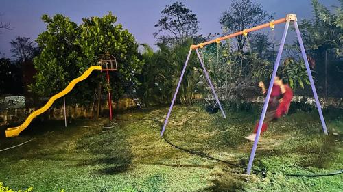 two children playing on a swing set in a yard at ARNAV VILLA Farmhouse & Resort in Vajapūr