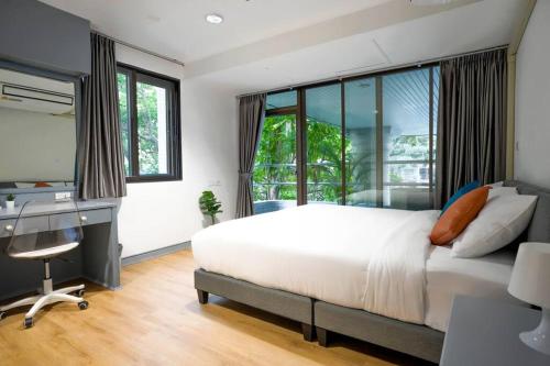 - une chambre avec un lit blanc, un bureau et une fenêtre dans l'établissement Cozy 2BR Apt in Central Bangkok 5 mins to BTS MattandCo, à Bangkok