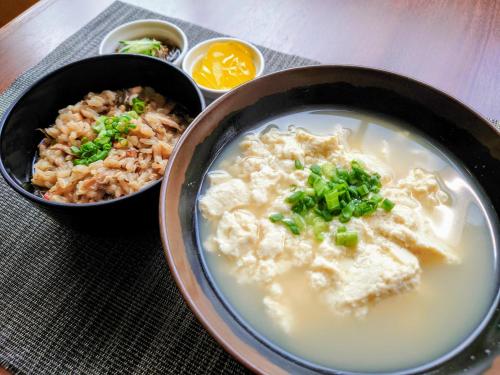a bowl of soup with rice and green onions on a table at Okinawa Hotel Precia in Naha