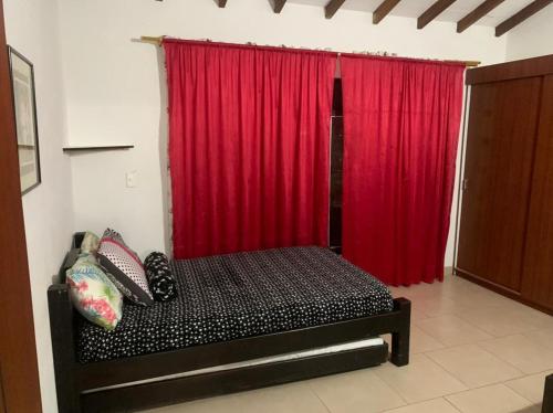 1 dormitorio con cortina roja y cama con almohadas en Balcones de la Casona, en Guatapé