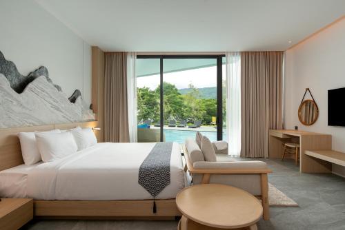 Timberton Resort Khaoyai في Ban Tha Maprang: غرفة فندقية بسرير ونافذة كبيرة