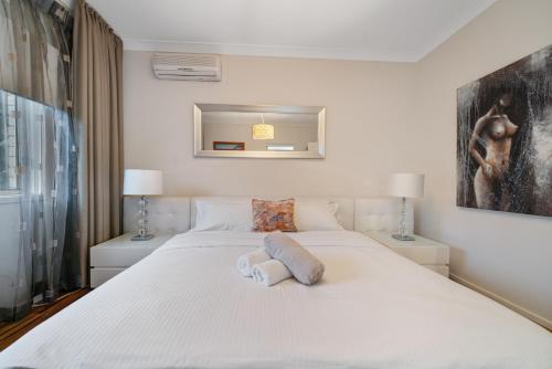 a bedroom with a large white bed with two lamps at Lakeside Hideaway in Mannering Park