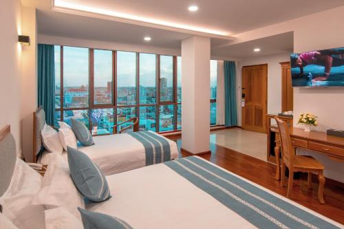 Habitación de hotel con 2 camas y escritorio en Dragon Phoenix Hotel en Mandalay