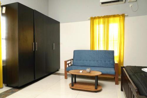 a bedroom with a blue chair and a coffee table at ORANGE VALLEY TOWN RESIDENCY in Trivandrum