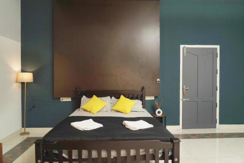 a bedroom with a bed with yellow pillows at ORANGE VALLEY TOWN RESIDENCY in Trivandrum