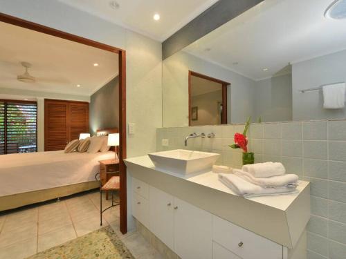 uma casa de banho com um lavatório, uma cama e um espelho. em Cassowary Villa 1 - Short Walk to Beach and Town em Port Douglas