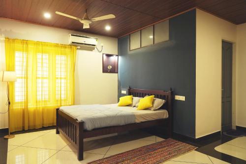 1 dormitorio con 1 cama con almohadas amarillas en ORANGE VALLEY TOWN RESIDENCY, en Trivandrum