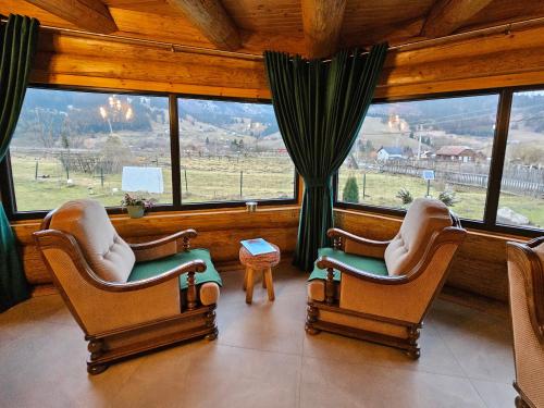 2 Stühle in einem Zimmer mit einem großen Fenster in der Unterkunft ORTOAIA CHALET in Dorna-Arini