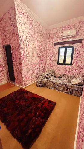 una camera da letto con carta da parati rosa, un letto e un tappeto di Tiguent palace a Tiguent