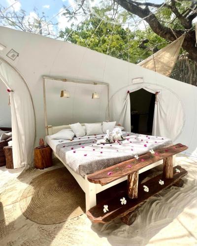 a bed in a tent with flowers on it at Rock and Sea Resort in Watamu