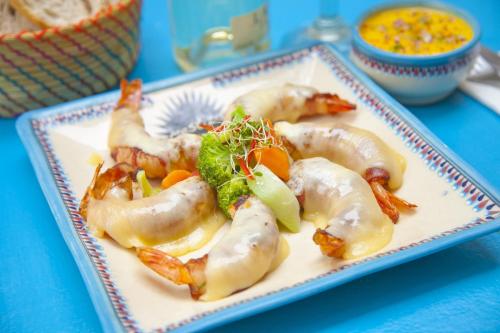 a plate of shrimp and vegetables on a blue table at Mestizo Gallery in Tulum