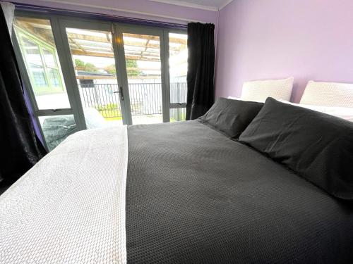 a bedroom with a white bed with a window at Mango at the Lake sleeps 8 in Mangakino