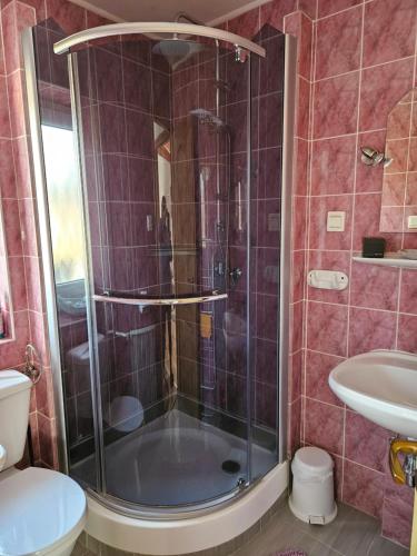 a bathroom with a shower with a toilet and a sink at Laguna apartman Bogács in Bogács