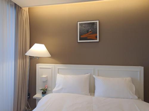 a bed with white pillows and a picture on the wall at Haeundae Ocean Family in Busan