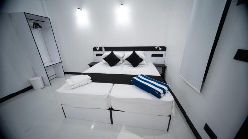 a small white room with two beds and pillows at Sunset Beach Stay at Mathiveri in Mathiveri