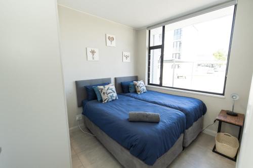 a bedroom with a blue bed with a large window at First Class Apartment At Bella in Summerstrand