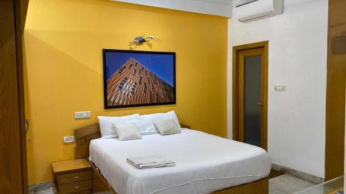 a bedroom with a white bed with a yellow wall at VISTAHOMES in Hyderabad