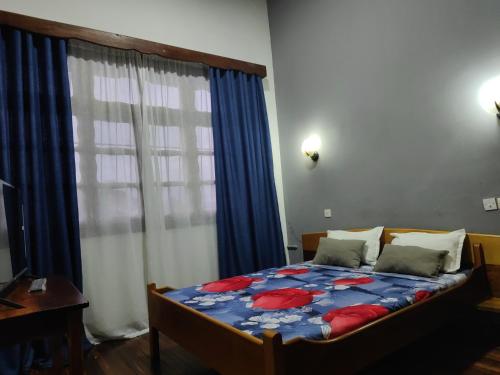 a bedroom with a bed and a window with blue curtains at Hôtel Diamant Antsirabe in Antsirabe