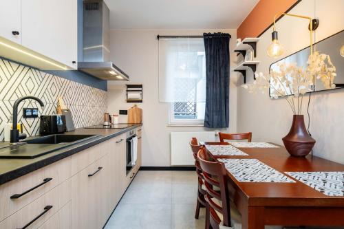 a kitchen with a wooden table and a kitchen with a sink at Maple Tree Premium Apartment Mokotow in Warsaw