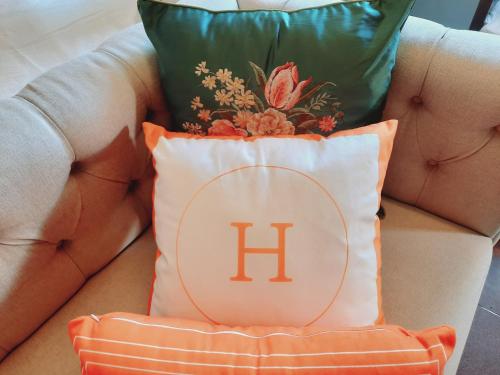 a pillow with the h on it sitting on a chair at Villia magnolia sanur bali 巴厘島玉蘭別墅 in Denpasar