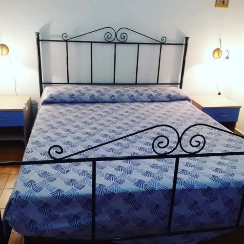 a bed with a blue comforter with two tables at Lampedusa Low Prices in Lampedusa
