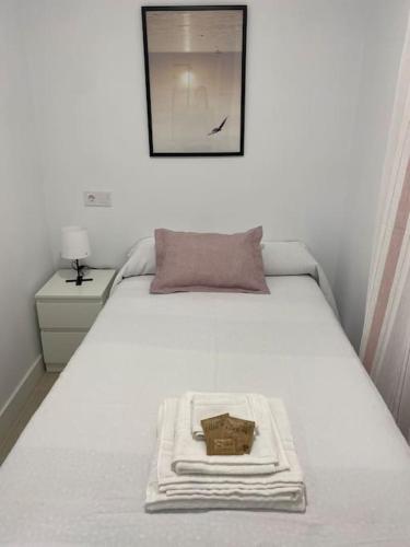a white bed with a basket on top of it at Alojamiento Baeza California 4B in Baeza