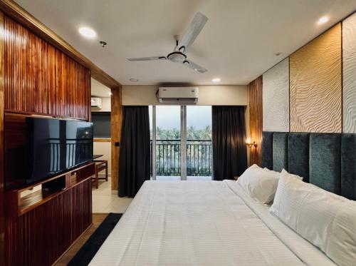 a bedroom with a large bed and a television at The Habitat Suites in Guruvāyūr