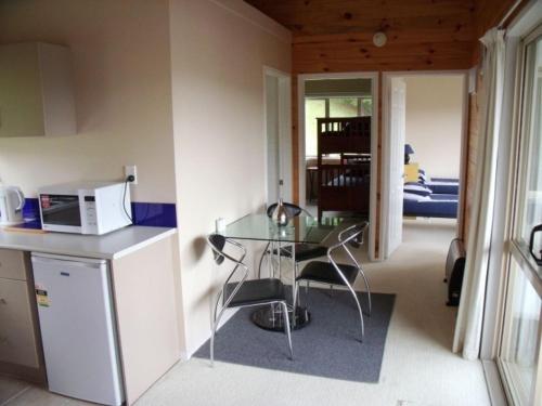 a kitchen with a glass table and a microwave at Whangarei Holiday Houses in Whangarei