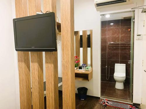 a bathroom with a toilet and a tv on a wall at RG Hotel in Air Hitam