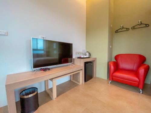 a living room with a television and a red chair at Zhaohong homestay in Yuchi