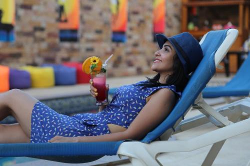 une femme assise sur une chaise avec un verre dans l'établissement Carmine Hotel Dahab, à Dahab