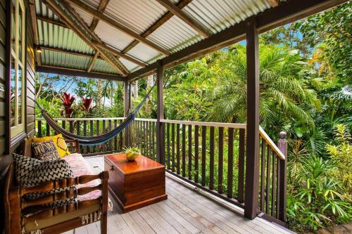 a porch with a hammock and a bench on a deck at Coco's Cottage in the Byron Bay Hinterland in Bangalow