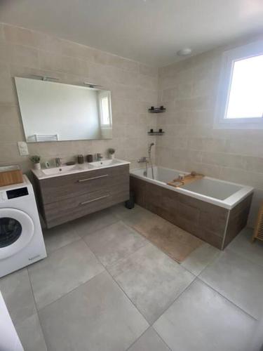 La salle de bains est pourvue d'une baignoire, d'un lavabo et d'un lave-linge. dans l'établissement Maison au cœur de la campagne, à Saint-Romans
