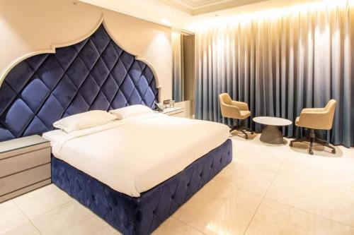 a bedroom with a large bed with a blue headboard at SWARN INN AND SUITES in Muzaffarnagar