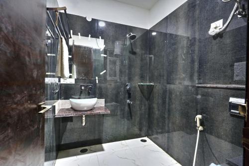 a black bathroom with a sink and a shower at The Noble Suites, Near Spectrum Mall in Noida